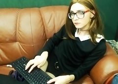 Nerdy young shemale in uniform pleases herself on the couch