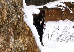 Brunette hot young chick walks in the winter forest and pisses behind the rock