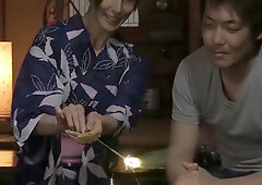 Young Asian woman in a floral kimono ties a man's wrists with red rope before being bound in return