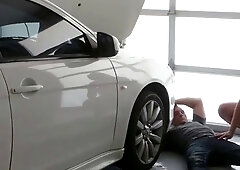 Two bulky fellows standing near a white sedan car in the