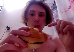 Nude damsel munches burger while on the rest room