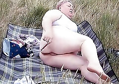whore masturbates twat with a toy in the field