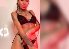 Tattooed thighs tilt back below pink shower light