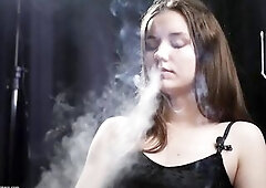 Indoors underneath soft lights, a enchanting brunette hair relaxes in a chair, lazily smokin', her calm expression blending with drifting smoky a