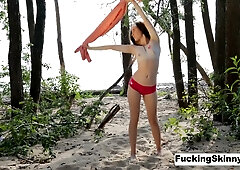 Skinny brunette bares herself on a pink towel at a secluded beach