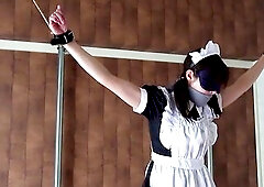 Inside her maid outfit petticoat. A remote-controlled sex toy, vibrating and suctioning, is held in place by white tights. With her arms and legs wide